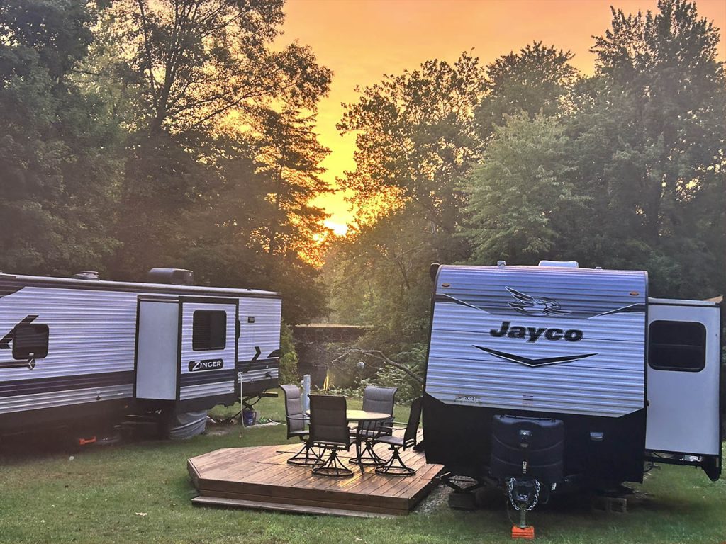 Seasonal RV Camping with Outdoor Living Space in Southwest Michigan Seasonal RV camping setup with deck and fire pit at sunset in Southwest Michigan campground